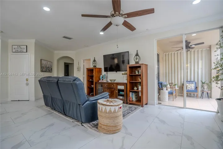 Large-format tile flooring, recessed ceiling lighting, central ceiling fan, and sliding glass doors providing external access
