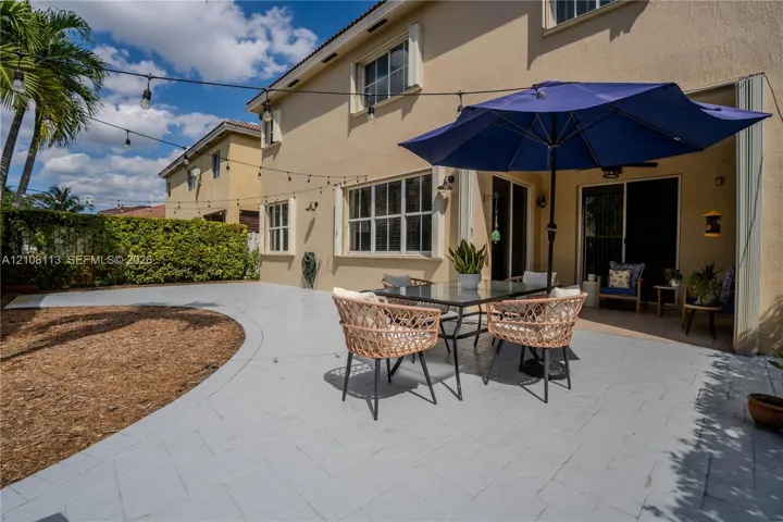 Stucco exterior featuring a paved patio, covered porch area, and integrated string lighting