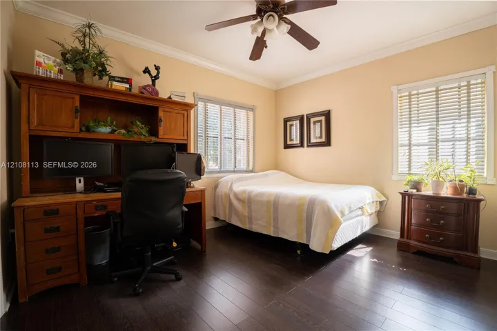 Dark wood-finish flooring, crown molding, and a central ceiling fan