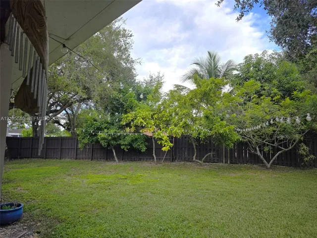 Expansive backyard featuring a lush lawn, mature trees, and a wooden privacy fence