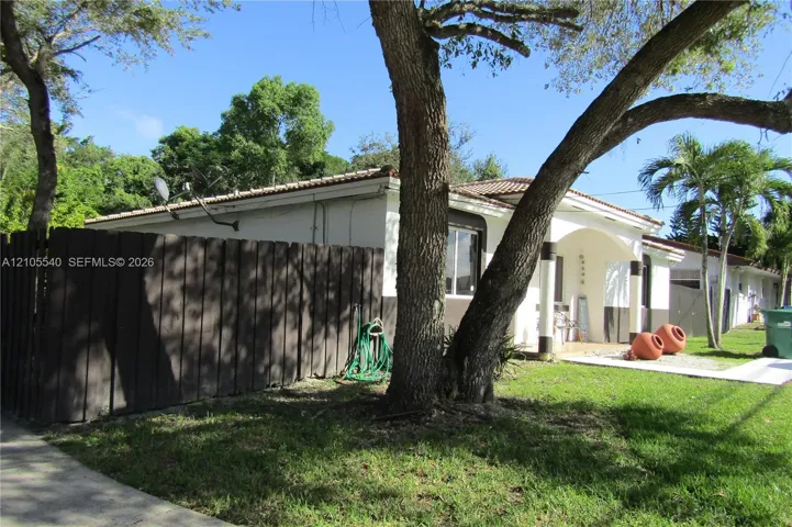 Picket fencing with a dark wood finish, mature trees, and a manicured lawn