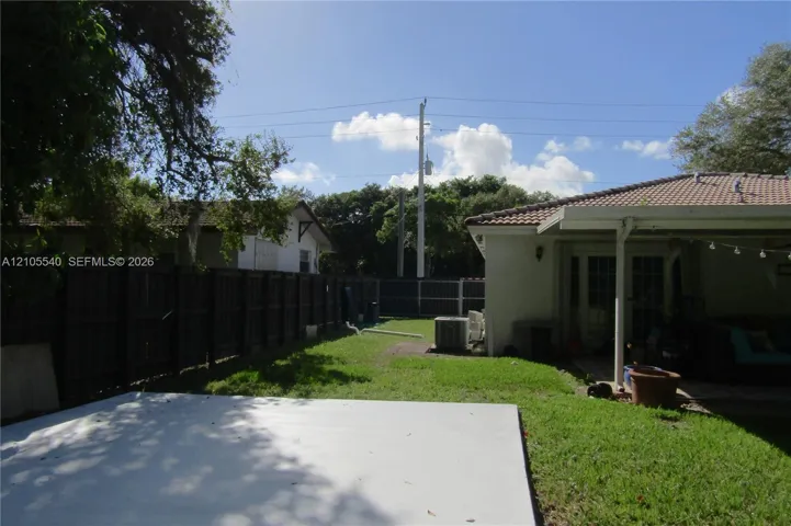 Expansive outdoor space featuring a concrete patio, grassy lawn, and wood-panel fencing