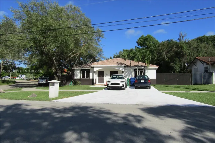 Single-story residence with a light-colored stucco exterior, dark trim, and a tile roof