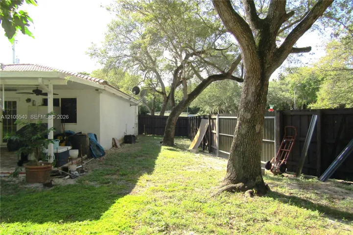 Expansive lawn area featuring mature trees and a privacy fence