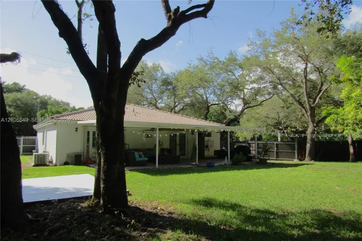 Expansive lawn with mature trees and a fenced perimeter