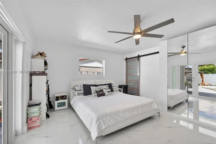 Polished tile flooring, mirrored closet doors, sliding barn-style door, and integrated ceiling fan with light fixture