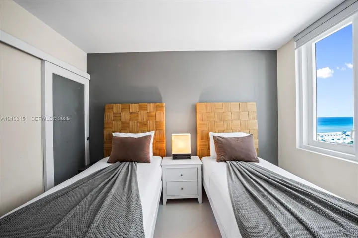 Room featuring a window with an ocean horizon, sliding door closet, and neutral-toned wall paint