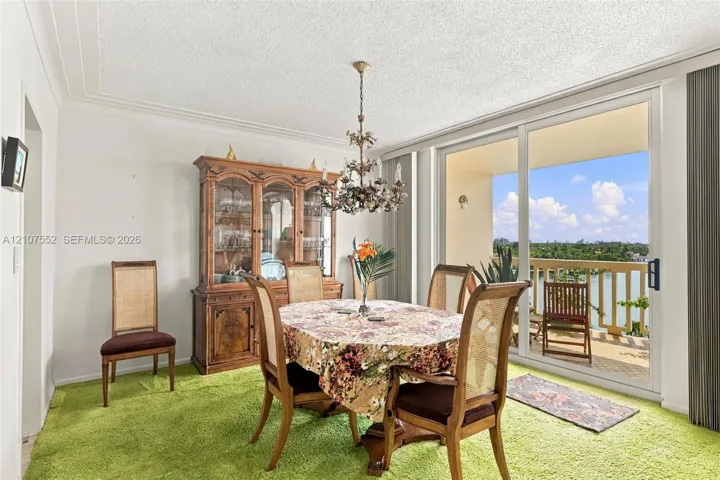 Dining area featuring a crystal chandelier and large glass sliding doors opening to an exterior balcony with water scenery