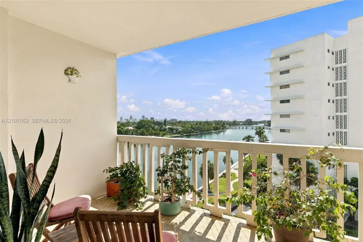 Covered balcony with a concrete balustrade and tile flooring, featuring expansive water and skyline scenery