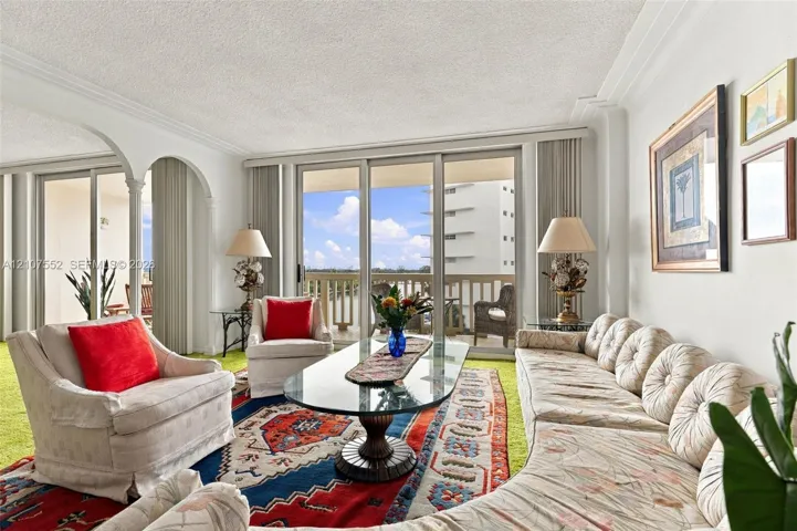 Living area featuring expansive floor-to-ceiling glass sliding doors, ornate arched architectural detailing, crown molding, and a private balcony