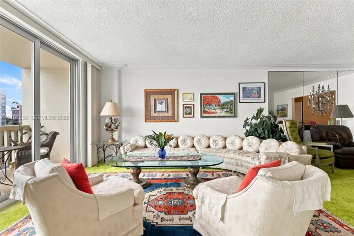 Living area featuring floor-to-ceiling glass sliding doors, private balcony access, and floor-to-ceiling mirrored wall panels