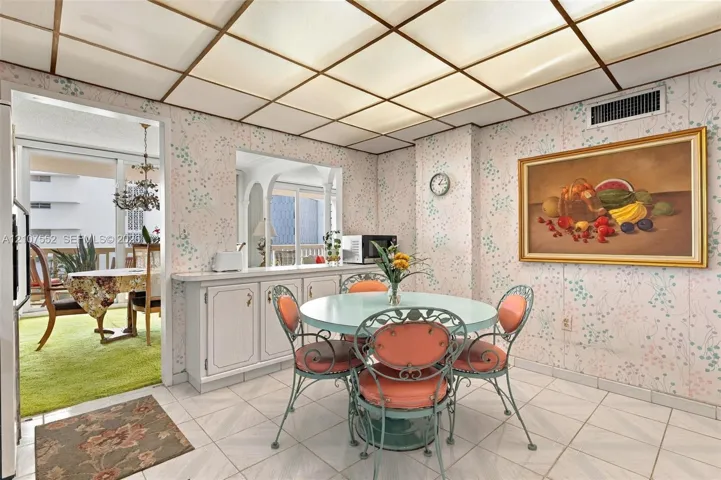 Grid-patterned drop ceiling with integrated lighting, ceramic tile flooring, and built-in cabinetry featuring a countertop pass-through