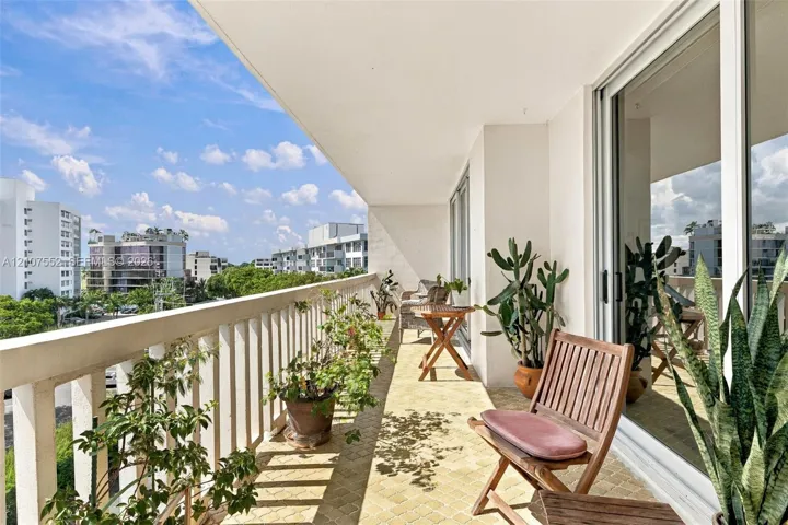 Covered balcony featuring patterned tile flooring, white vertical railings, and large sliding glass doors
