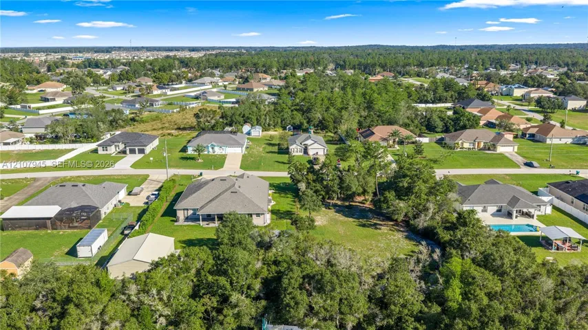 Aerial view of a residential lot featuring expansive acreage, mature tree clusters, and established perimeter vegetation