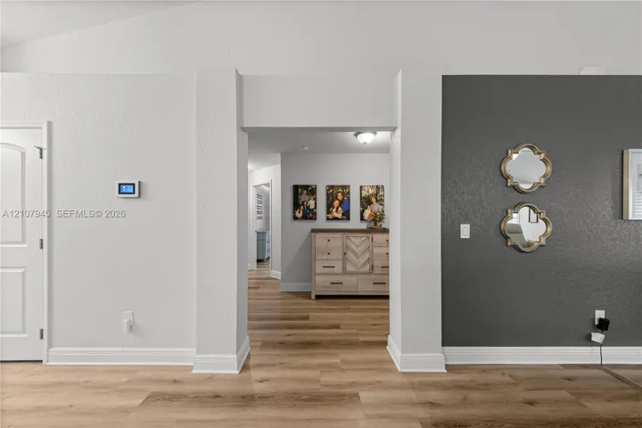 Interior space featuring wide-plank wood-finish flooring, a dark charcoal accent wall, and a central architectural archway
