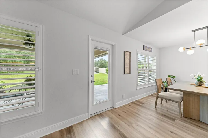 Vaulted ceiling featuring wood-finish flooring, plantation shutters, and a modern linear chandelier