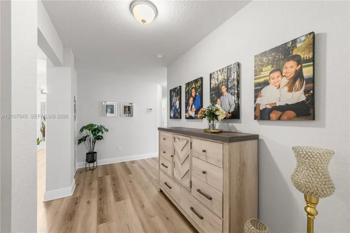 Interior hallway featuring wood-finish flooring, crisp neutral wall paint, and a ceiling-mounted light fixture