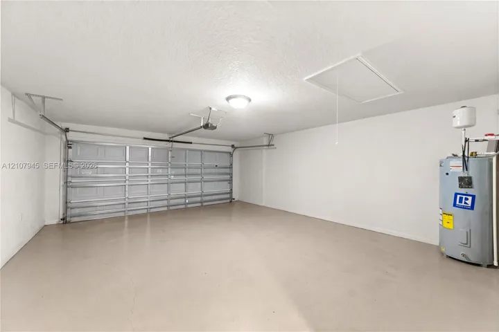 Attached garage featuring a multi-panel steel door, ceiling-mounted lighting, and an installed water heater