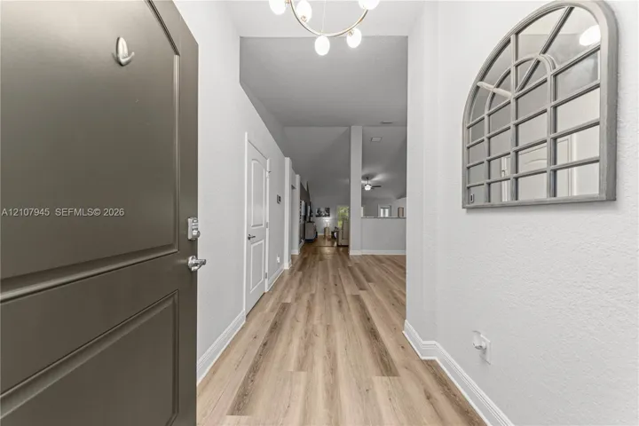 Entryway featuring wood-finish flooring, a multi-light chandelier, and a solid panel door