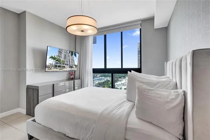 Floor-to-ceiling windows, drum pendant lighting, neutral textured wall covering, and large-format tile flooring
