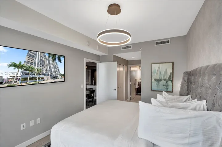 Circular modern LED pendant light fixture, neutral wall color palette, and light-colored tile flooring