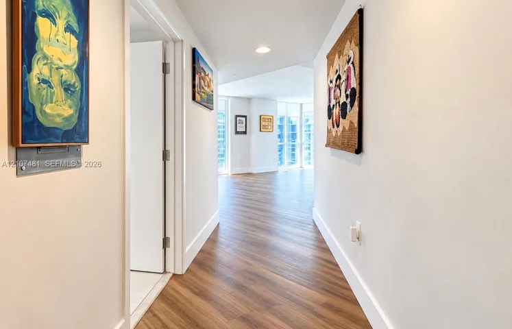 Hallway featuring wood-finish flooring, recessed ceiling lighting, and floor-to-ceiling windows