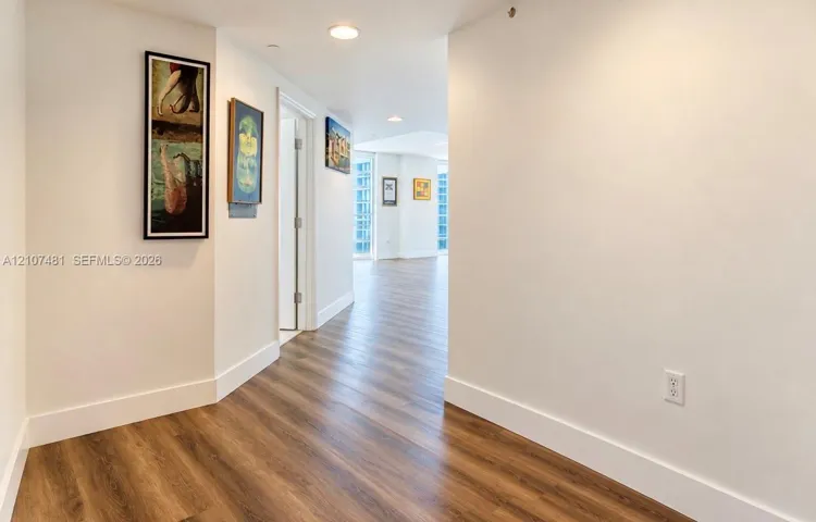 Interior corridor featuring wood-finish flooring, recessed lighting, and crisp white wall finishes