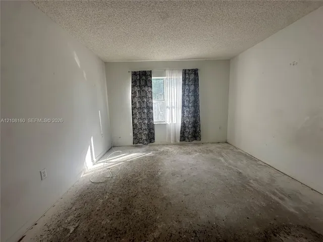 Interior space featuring a single-pane window with a horizontal orientation, white walls, and a textured ceiling finish