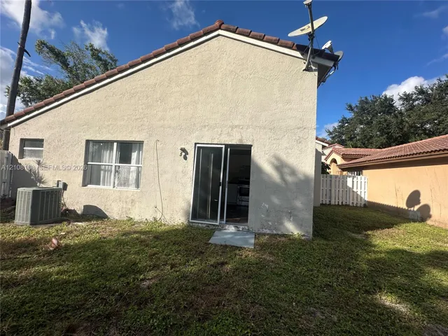 Stucco exterior featuring a tiled roof, sliding glass doors, and a private yard with white vinyl fencing