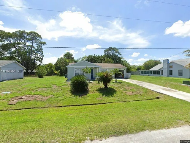 Single-story residence featuring a light-toned exterior, concrete driveway, attached garage, and mature landscaping