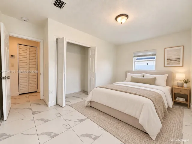 Large-format tile flooring with a light veined pattern, dual closets with bi-fold louvered doors, and a neutral color palette