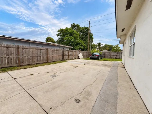 Exterior concrete driveway featuring a wood-panel perimeter fence