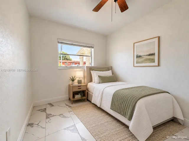 Neutral-toned room featuring large-format tile flooring with gray veining, a single-hung window, and a ceiling fan with integrated lighting