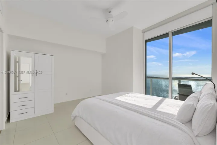 Floor-to-ceiling sliding glass doors, neutral tile flooring, built-in white cabinetry, and a ceiling-mounted fan