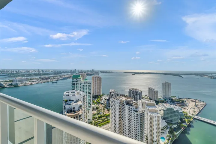 Elevated balcony featuring a white metal railing overlooking a coastal cityscape and open water
