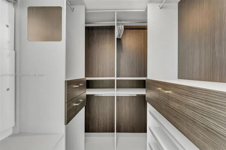 Custom closet system featuring wood-finish cabinetry, built-in shelving, integrated hanging rods, and drawers with metallic hardware