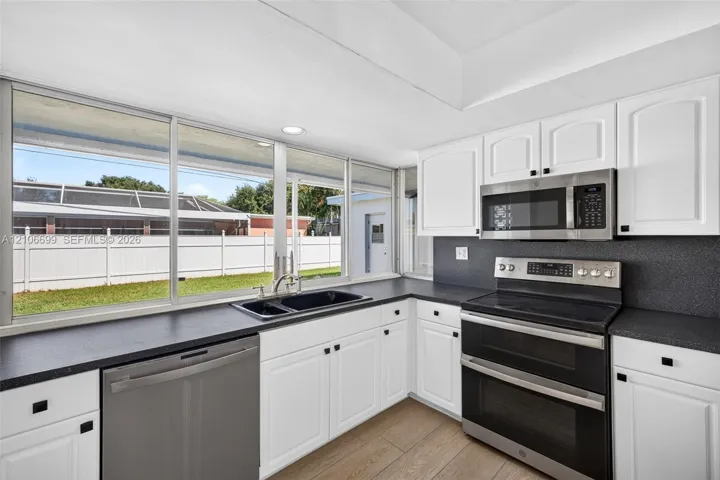 Open concept kitchen w/ updated plank wood look tile, stainless appliances approx 2020
