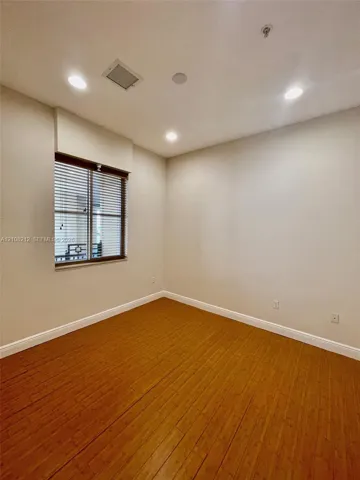 Room featuring wood-finish flooring, recessed lighting, and a window with horizontal blinds