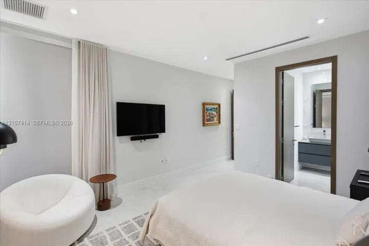 Neutral-toned interior featuring recessed lighting, smooth wall finishes, stone-style flooring, and floor-to-ceiling drapery