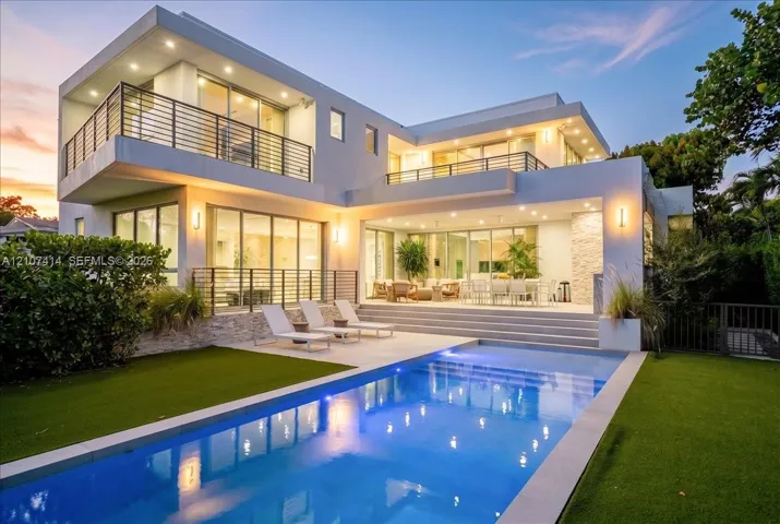 Contemporary exterior featuring tiered balconies with metal railings, expansive floor-to-ceiling glass sliding doors, recessed lighting, stone veneer accents, and an integrated swimming pool with a stone-paved deck