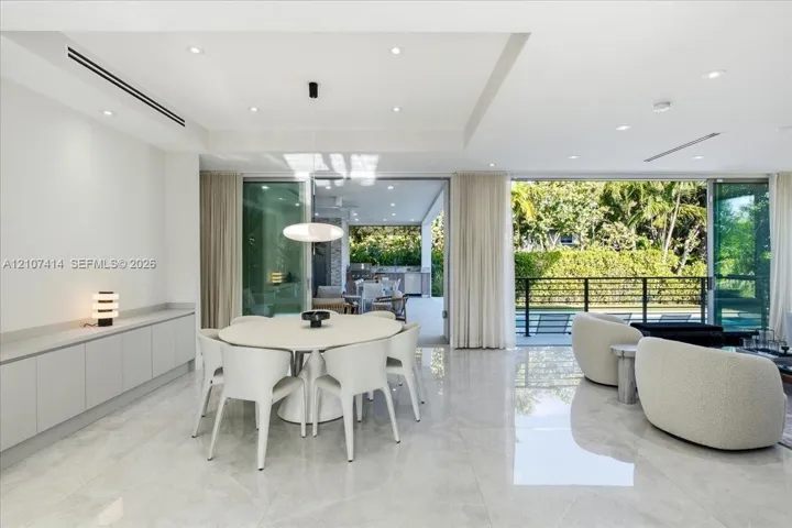 Large-format polished tile flooring, recessed ceiling lighting, built-in floor-to-ceiling cabinetry, and expansive multi-panel sliding glass doors