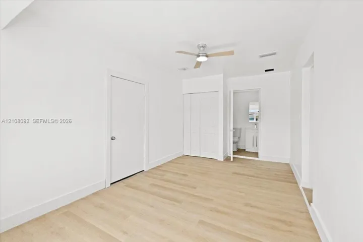 Room featuring wood-finish flooring, a neutral color palette, ceiling fan with integrated lighting, and white six-panel doors