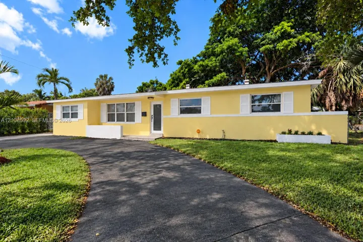 Single-story exterior featuring a stucco facade, curved asphalt driveway, built-in concrete planter, and window shutters