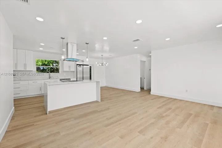 Kitchen featuring white cabinetry, solid-surface countertops, wood-finish flooring, recessed lighting, and a stainless steel range hood