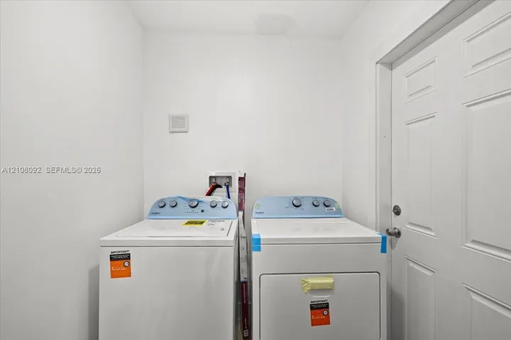 Dedicated laundry area featuring a white six-panel door and plumbing hookups for a top-load washer and dryer