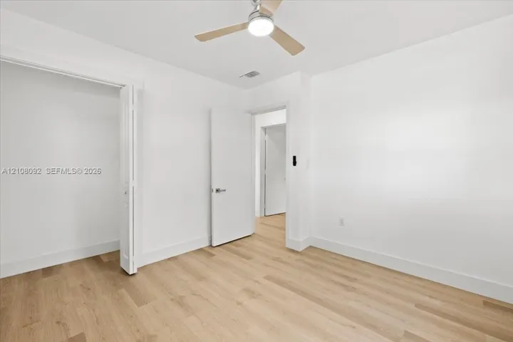 Room featuring wood-finish flooring, a ceiling fan with integrated lighting, and a bifold closet door