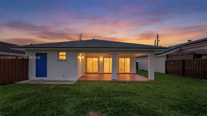 Rear exterior featuring a covered patio, tiled flooring, glass sliding doors, and privacy fencing