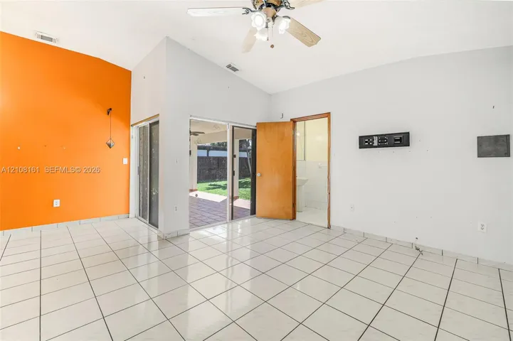 Vaulted ceiling, ceramic tile flooring, ceiling fan with light fixture, and sliding glass doors