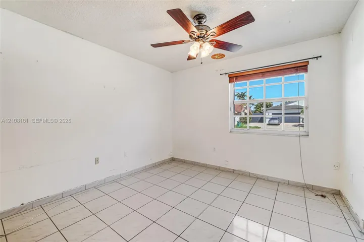 Interior space featuring ceramic tile flooring, a multi-blade ceiling fan with integrated lighting, and a multi-pane window with horizontal blinds