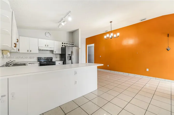Kitchen featuring a peninsula countertop, white cabinetry, built-in stainless steel appliances, track lighting, and tiled flooring